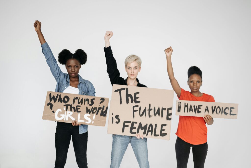 Diverse women raising fists and holding feminist signs, showcasing empowerment and unity.
