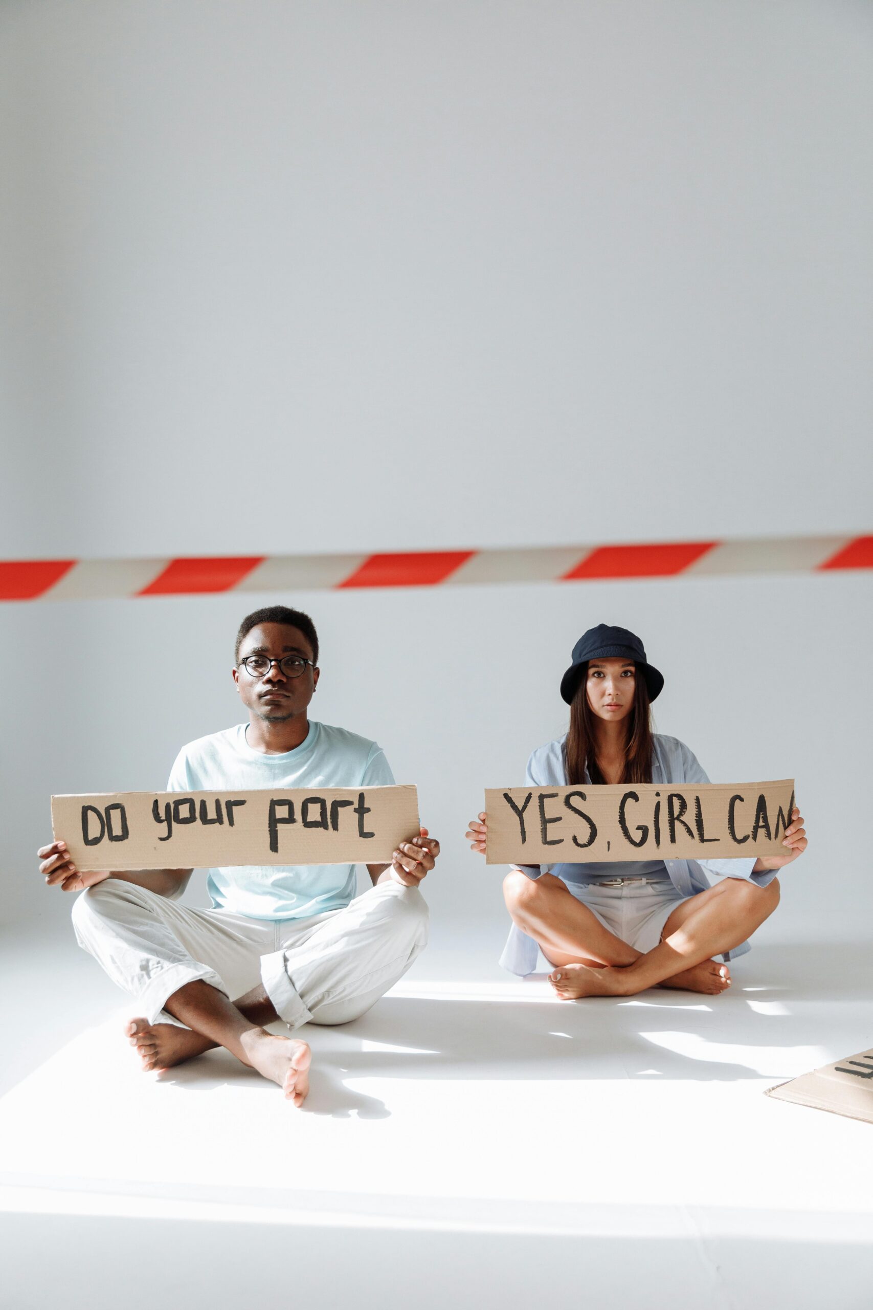 Two people sit with motivational protest signs in a studio setting.